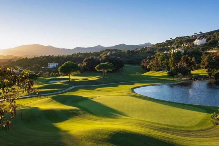 Home Massage in Los Naranjos with SENSE8 massage A golf course at dawn, with trees and a lake, surrounded by hills in Marbella